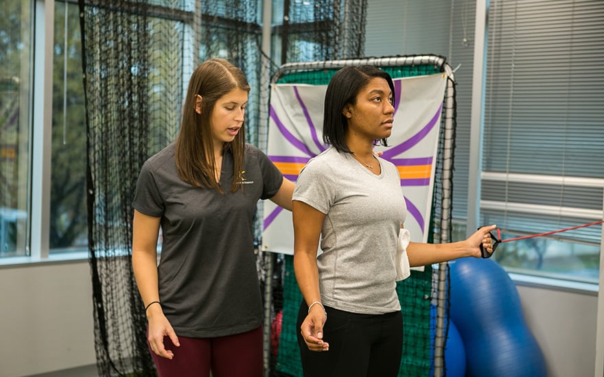A physical therapist guides a patient through shoulder rehabilitation.
